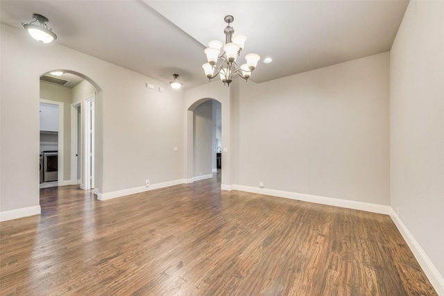 spare room with dark hardwood / wood-style flooring, washer / clothes dryer, and a notable chandelier