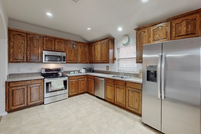 kitchen with brown cabinets, stainless steel appliances, light countertops, a sink, and recessed lighting