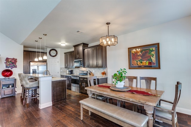 dining room with sink, an inviting chandelier, and dark hardwood / wood-style flooring