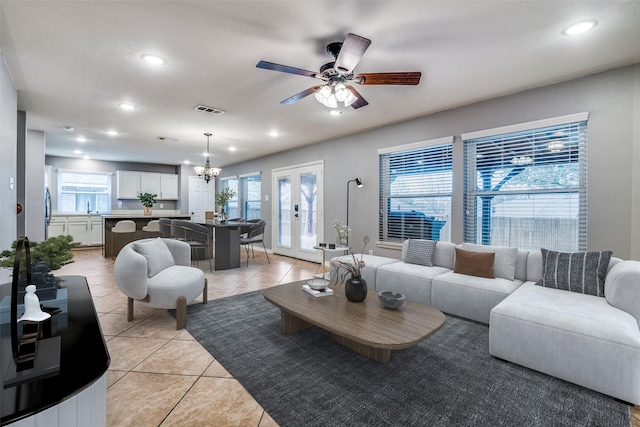 tiled living room with sink, ceiling fan with notable chandelier, french doors, and a healthy amount of sunlight