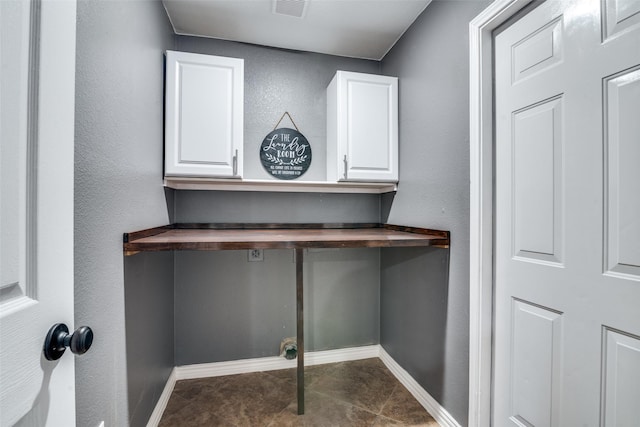 washroom featuring electric dryer hookup and dark tile patterned flooring