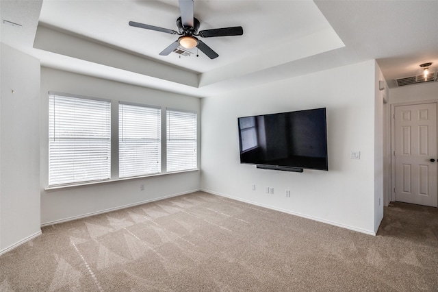 unfurnished living room with light carpet, a raised ceiling, and ceiling fan