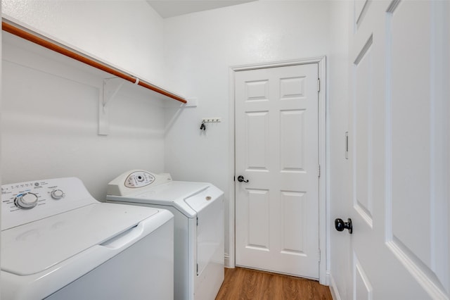 laundry area with washer and clothes dryer and light wood-type flooring