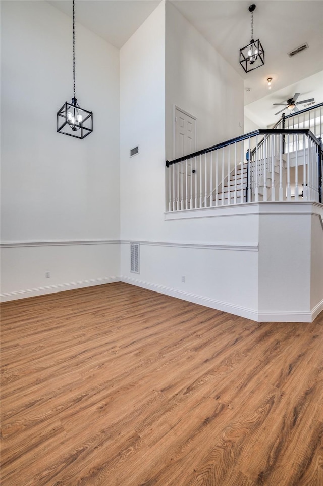 staircase featuring ceiling fan with notable chandelier and wood-type flooring