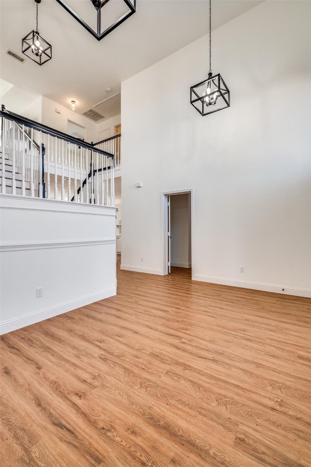 unfurnished living room featuring a towering ceiling and light wood-type flooring