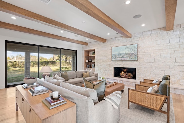 living room featuring beam ceiling, a fireplace, and light wood-type flooring