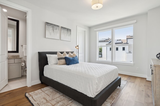 bedroom with ensuite bath and light wood-type flooring