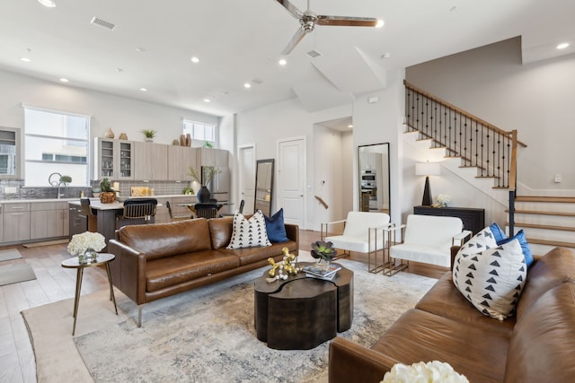 living room with sink, light hardwood / wood-style flooring, ceiling fan, and a high ceiling