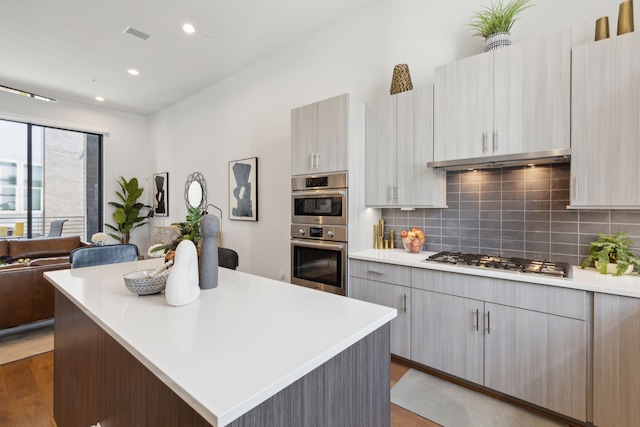 kitchen featuring stainless steel appliances, tasteful backsplash, a center island, and hardwood / wood-style floors