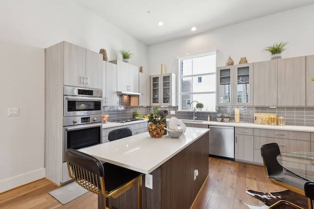 kitchen with sink, a kitchen breakfast bar, a kitchen island, stainless steel appliances, and backsplash