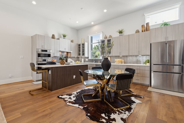 kitchen featuring a breakfast bar, a center island, light wood-type flooring, stainless steel appliances, and backsplash