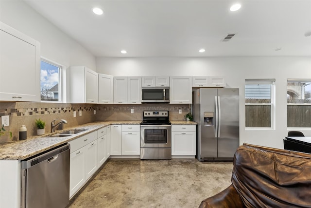 kitchen with sink, appliances with stainless steel finishes, light stone counters, tasteful backsplash, and white cabinets