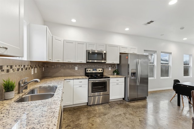 kitchen with sink, white cabinetry, stainless steel appliances, tasteful backsplash, and light stone countertops