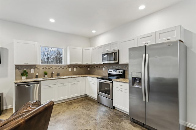 kitchen featuring tasteful backsplash, sink, white cabinets, light stone counters, and stainless steel appliances