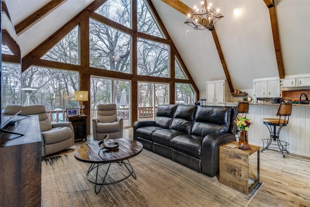 living room featuring an inviting chandelier, beam ceiling, and light hardwood / wood-style flooring