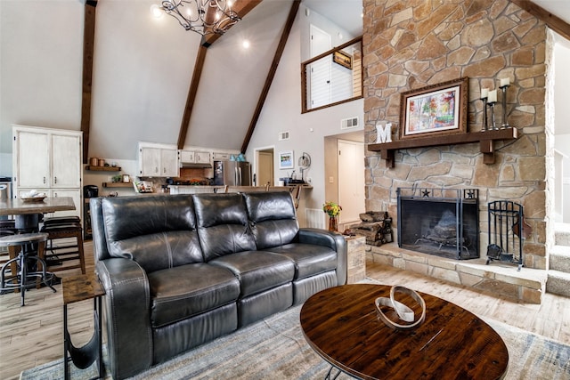 living room with high vaulted ceiling, a fireplace, beam ceiling, an inviting chandelier, and light hardwood / wood-style flooring