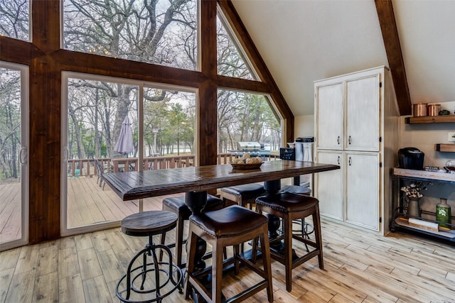 dining space with high vaulted ceiling and light hardwood / wood-style floors