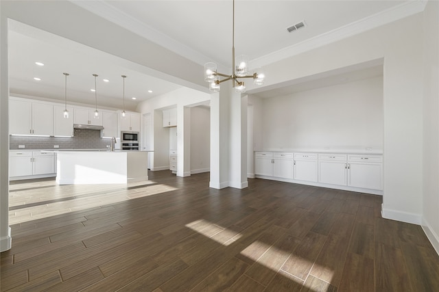 unfurnished living room with sink, a notable chandelier, ornamental molding, and dark hardwood / wood-style floors