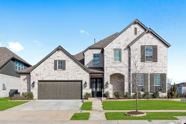 french country inspired facade featuring brick siding, concrete driveway, cooling unit, french doors, and a front yard