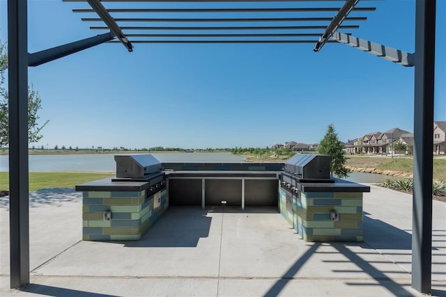 view of patio with a water view and an outdoor kitchen