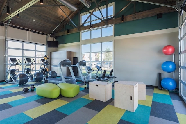 exercise room featuring plenty of natural light, wood ceiling, and high vaulted ceiling