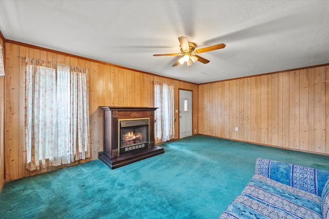 unfurnished living room with ceiling fan, ornamental molding, wooden walls, and dark colored carpet