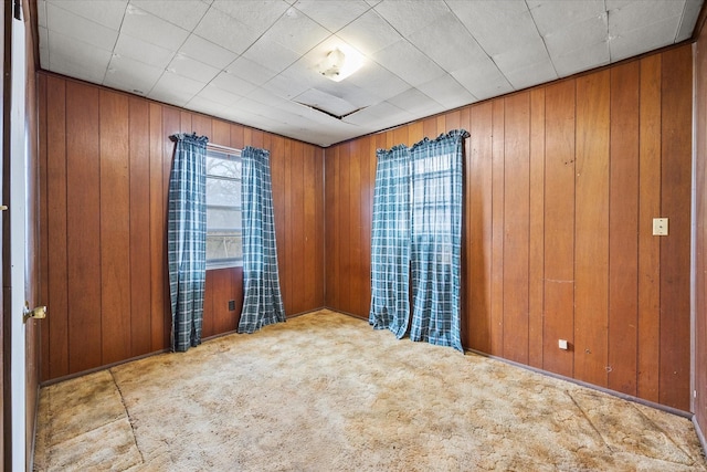 carpeted empty room with wood walls