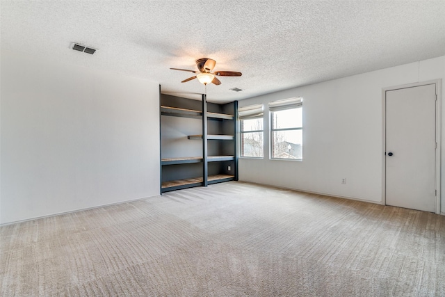 carpeted empty room featuring ceiling fan and a textured ceiling