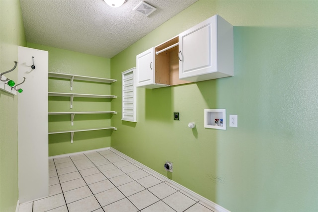 laundry area featuring electric dryer hookup, hookup for a washing machine, cabinets, a textured ceiling, and light tile patterned flooring