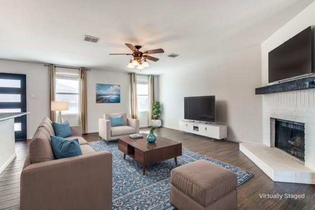 unfurnished living room with ceiling fan, dark hardwood / wood-style flooring, and a brick fireplace