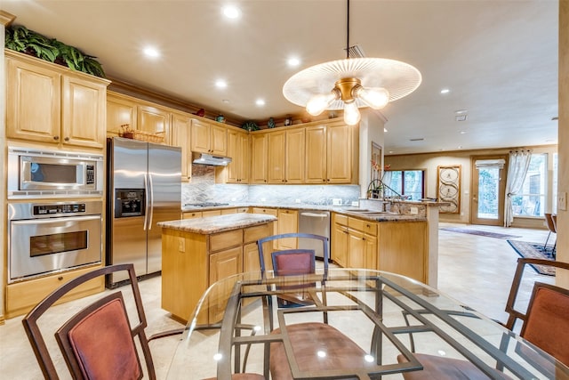 kitchen featuring light stone counters, decorative light fixtures, appliances with stainless steel finishes, kitchen peninsula, and decorative backsplash