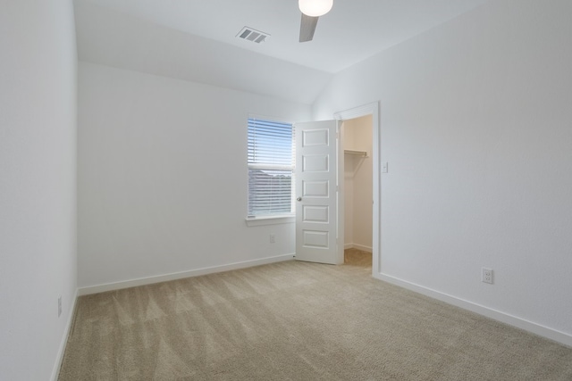 spare room featuring ceiling fan, vaulted ceiling, and light carpet