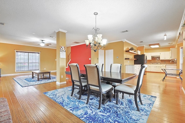 dining room featuring sink, crown molding, light hardwood / wood-style floors, a textured ceiling, and ceiling fan with notable chandelier