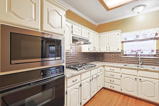 kitchen with built in microwave, sink, light wood-type flooring, stainless steel gas stovetop, and oven