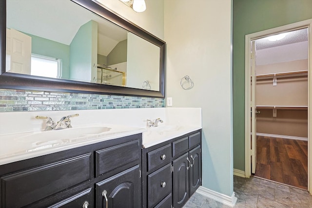 bathroom featuring a shower with door, vanity, and backsplash