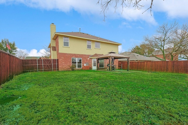 rear view of house featuring a gazebo and a yard