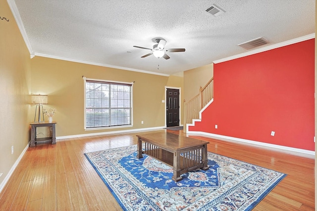 living room with ceiling fan, ornamental molding, wood-type flooring, and a textured ceiling