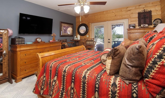 carpeted bedroom featuring wood walls, access to exterior, and french doors