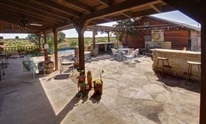 view of patio / terrace featuring ceiling fan and exterior bar