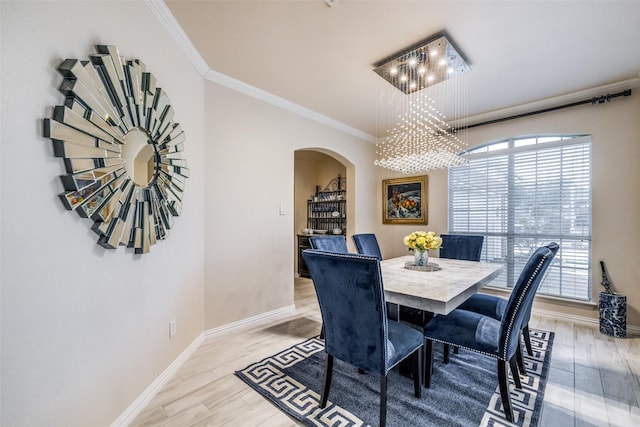 dining space featuring crown molding, an inviting chandelier, and light hardwood / wood-style floors