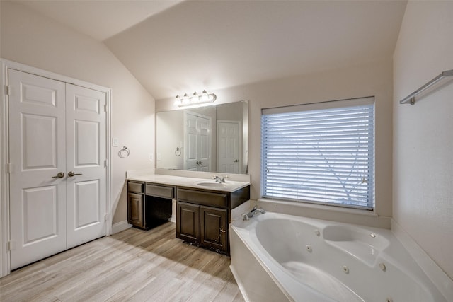 bathroom with vaulted ceiling, vanity, a bathtub, and hardwood / wood-style floors