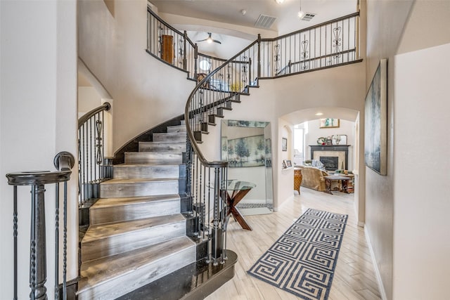 stairs with hardwood / wood-style flooring, a high ceiling, and a fireplace