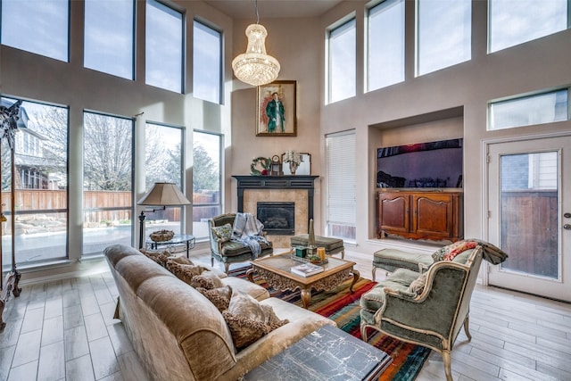 living room with a healthy amount of sunlight, a tiled fireplace, and light wood-type flooring