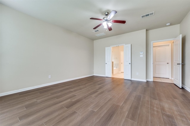 unfurnished bedroom featuring wood-type flooring, ceiling fan, and ensuite bathroom