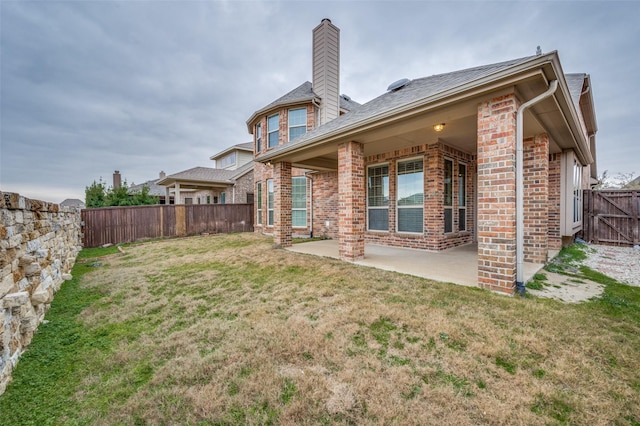 rear view of property featuring a yard and a patio area