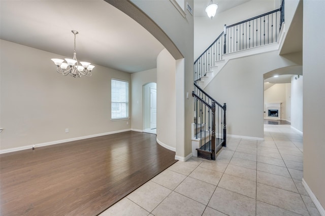 entryway with a towering ceiling, a notable chandelier, and light wood-type flooring