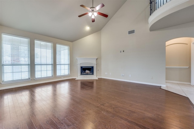 unfurnished living room with ceiling fan, wood-type flooring, and high vaulted ceiling