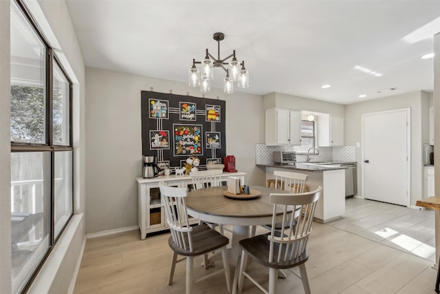 dining area with an inviting chandelier, sink, and light wood-type flooring