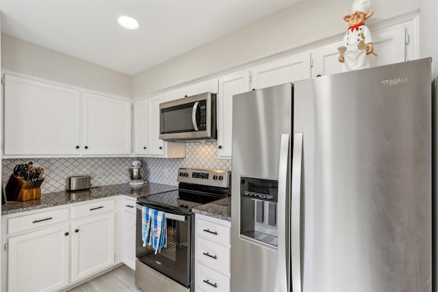 kitchen featuring backsplash, stainless steel appliances, dark stone counters, and white cabinets