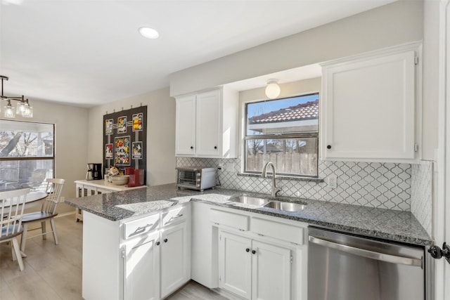 kitchen with white cabinetry, stainless steel dishwasher, and kitchen peninsula